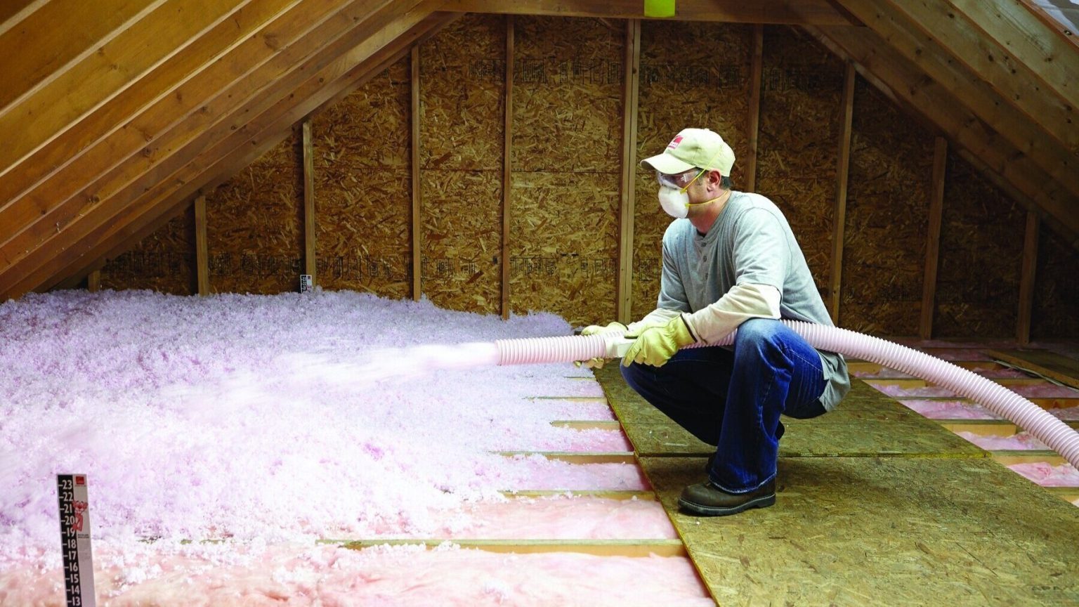Man installing pink insulation in attic.